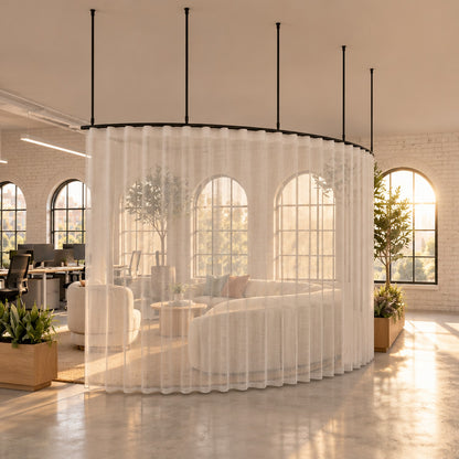 Zone A curved curtain track with a sheer wave curtain, suspended on drop tubes round a lounge beside an office walkway
